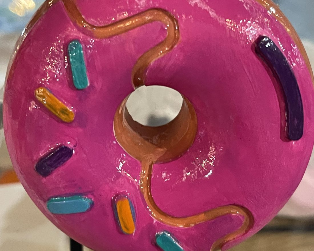 A finished hand-painted pink donut with sprinkles, made from a Creative Kids kit